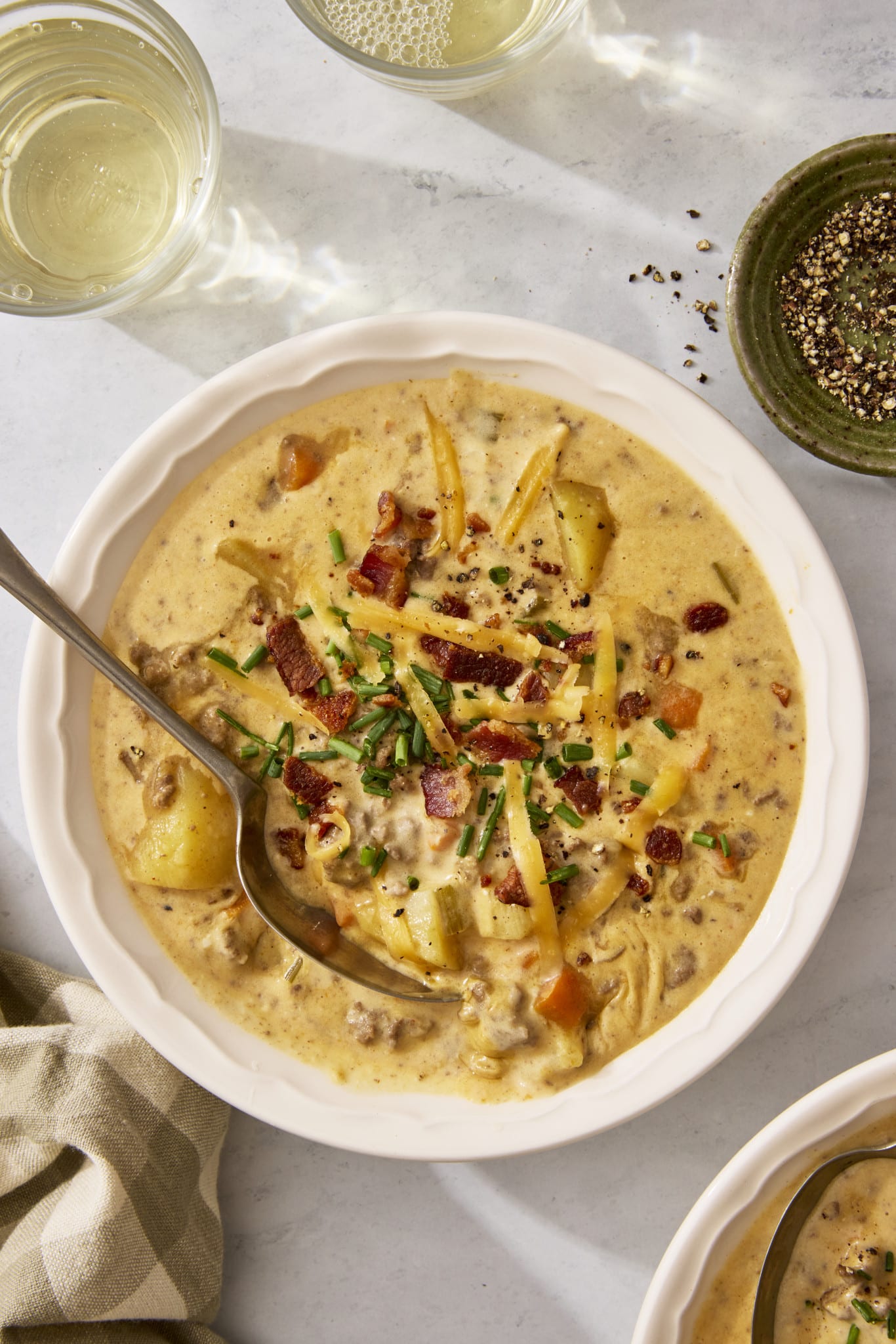 Cheeseburger soup in a bowl with a spoon digging in.