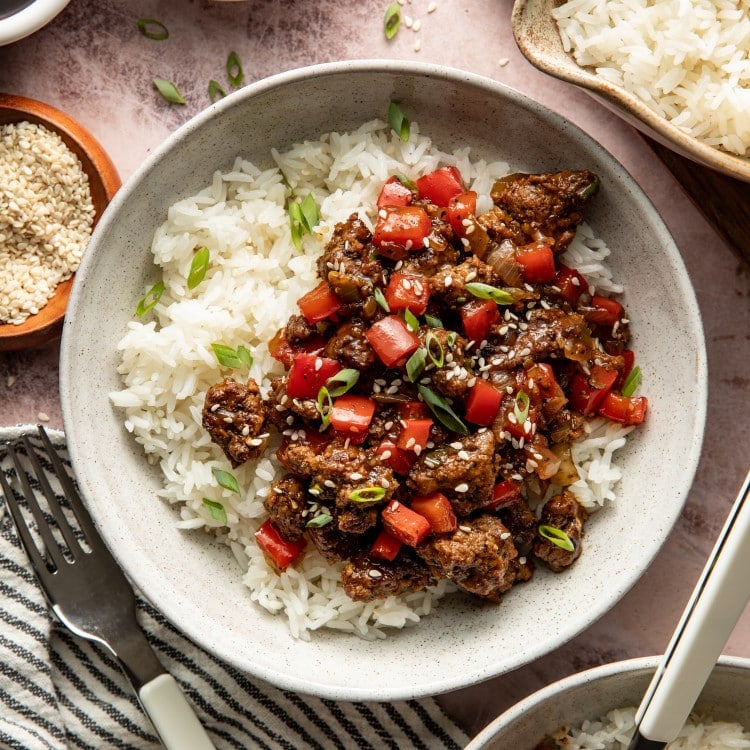 Honey garlic beef served over warm rice in a bowl.