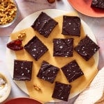 Date brownies sliced and sitting on a piece of parchment paper on a round tray.