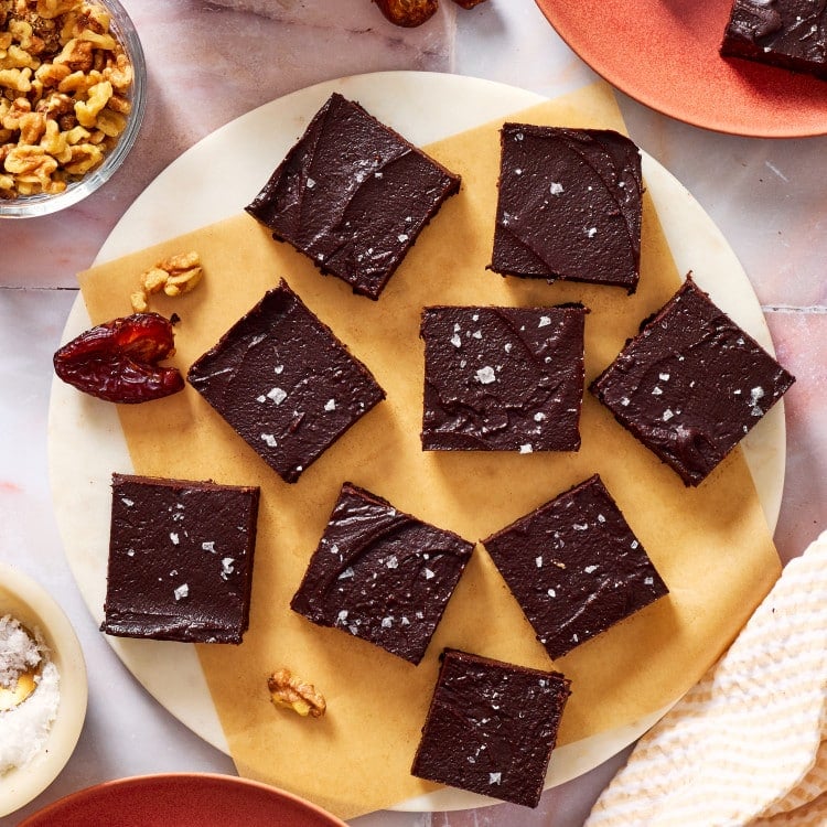 Date brownies sliced and sitting on a piece of parchment paper on a round tray.