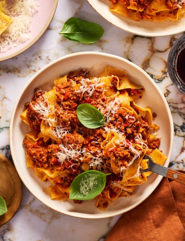 Pappardelle bolognese served in a bowl with a fork on the right side.