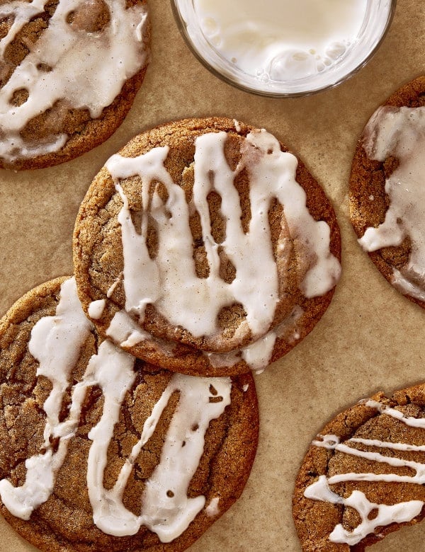 Two pumpkin butter cookies back and iced on parchment lined baking tray.