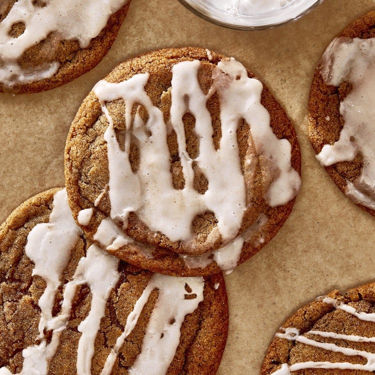 Two pumpkin butter cookies back and iced on parchment lined baking tray.