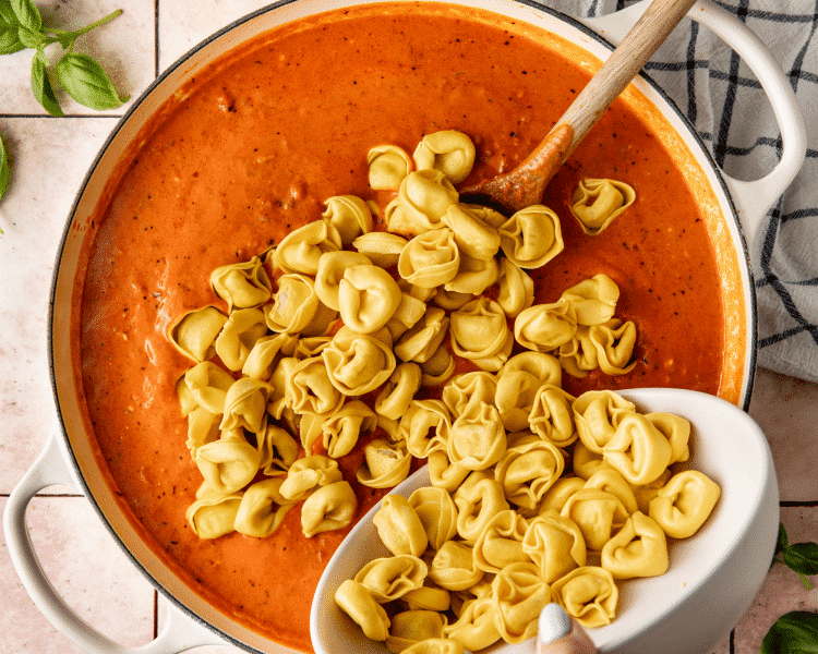 Adding cheese tortellini into sauce and beef mixture.