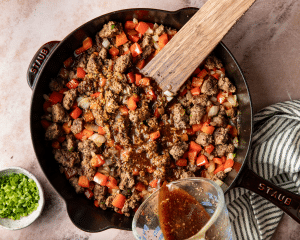 Pouring sauce over cooked beef and vegetables.