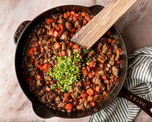 Adding green onions to finished honey garlic beef skillet.
