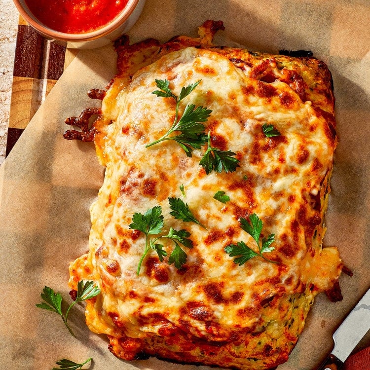 Chicken parmesan meatloaf baked and resting on parchment lined baking sheet and garnished with fresh parsley.