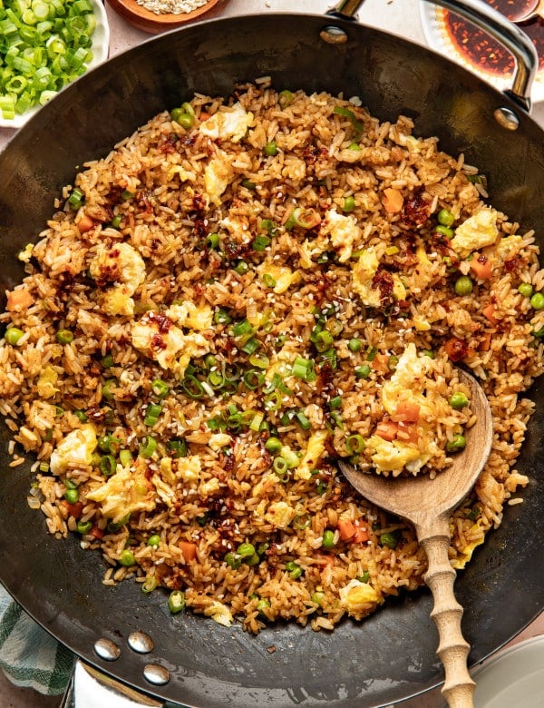 Chili crisp fried rice in a wok with wooden spoon.