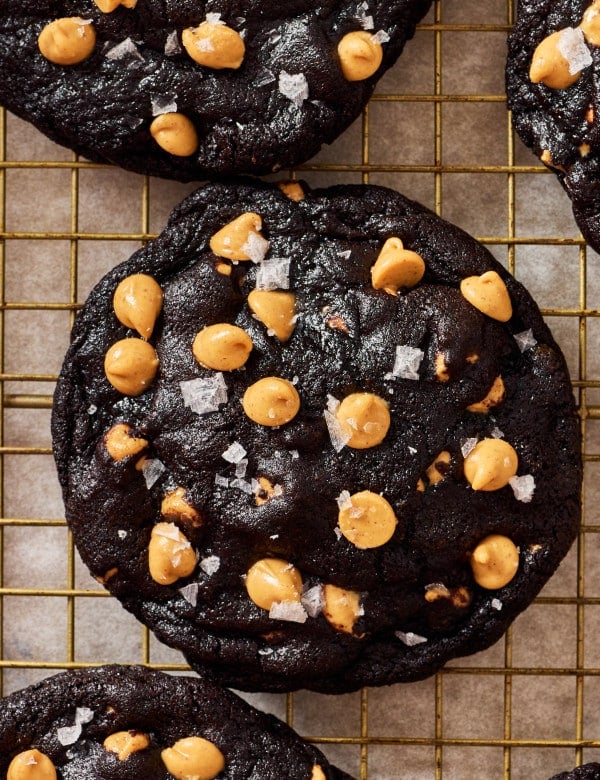 Chocolate peanut butter chip cookie sprinkled with flaky sea salt cooling on wire rack.