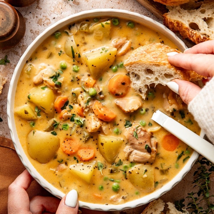 Dipping a piece of crusty bread into chicken stew.
