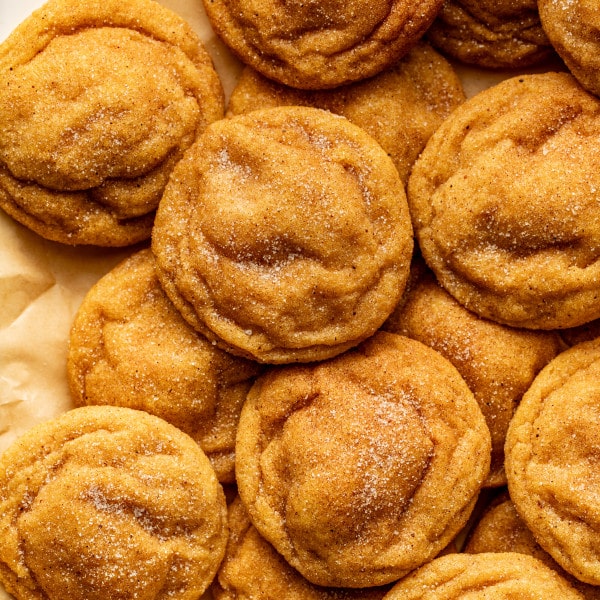 Pumpkin sugar cookies on parchment sheet after baking.