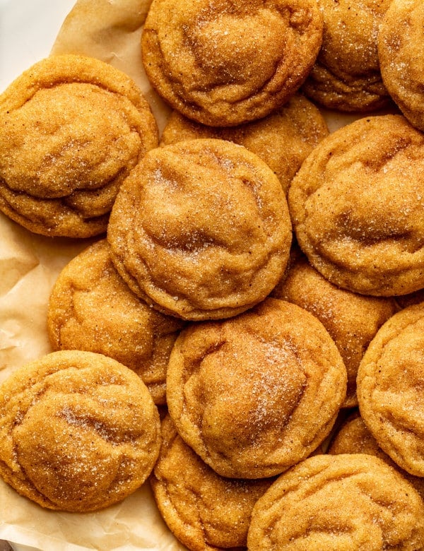 Pumpkin sugar cookies on parchment sheet after baking.