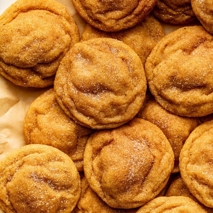 Pumpkin sugar cookies on parchment sheet after baking.