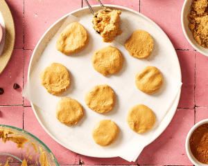 Scooping and flattening the peanut butter mixture on a plate and placing in the fridge to chill while you make and bake the cookies.