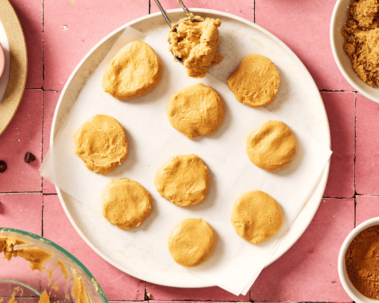 Scooping and flattening the peanut butter mixture on a plate and placing in the fridge to chill while you make and bake the cookies.