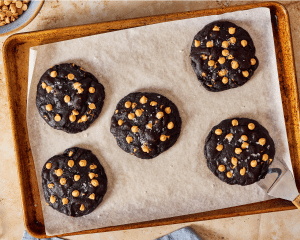 Five chocolate peanut butter cookies baked on parchment lined baking sheet.