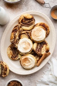Frosted and unfrosted cinnamon roll cookies on a large oval plate.