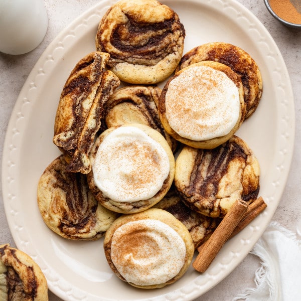 Frosted and unfrosted cinnamon roll cookies on a large oval plate.
