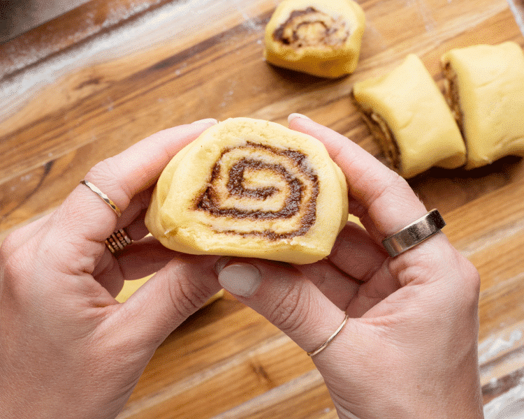 Cutting the rolled up cinnamon roll cookie dough into 20-24 individual cuts before rolling.