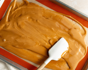 Spreading cooked toffee on prepared 9x13 baking pan.