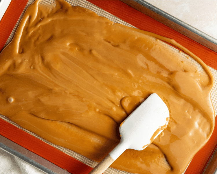 Spreading cooked toffee on prepared 9x13 baking pan.