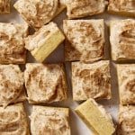 Frosted pumpkin sugar cookie bites cut into squares with two squares turned on their side to show the inside of the cookie.