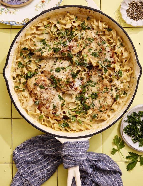 One-pot chicken and buttered noodles cooked in a large skillet and garnished with fresh parsley.