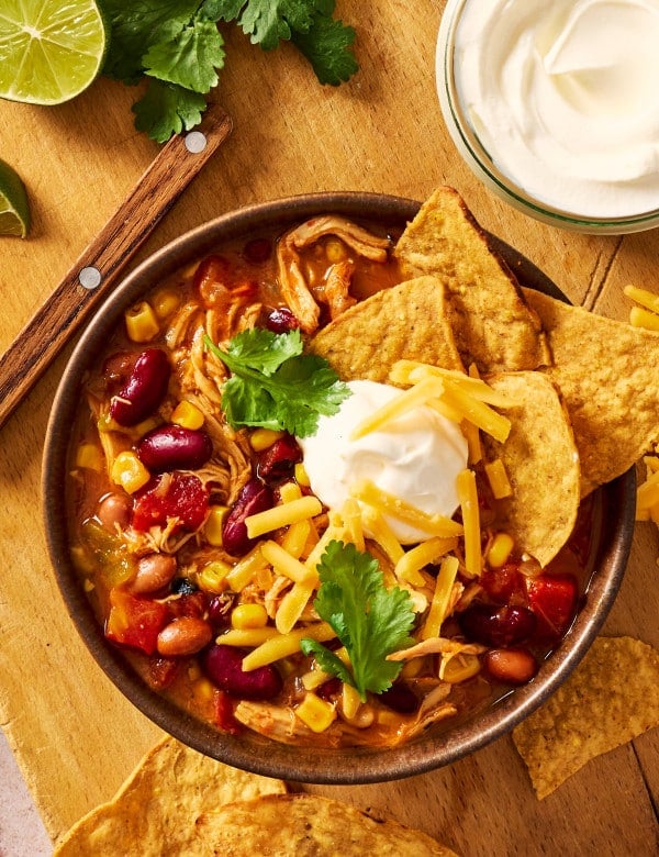 Chicken taco soup served in a bowl with toppings and tortilla chips.
