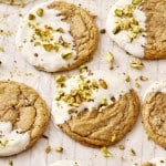 Brown butter sugar cookies dipped in white chocolate and garnished with chopped pistachios on wax paper.