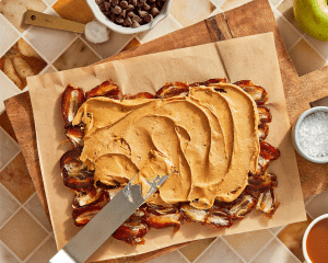 Spreading peanut butter on top of smashed dates.