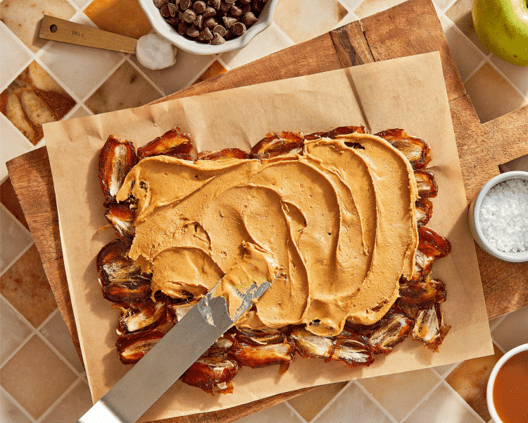 Spreading peanut butter on top of smashed dates.
