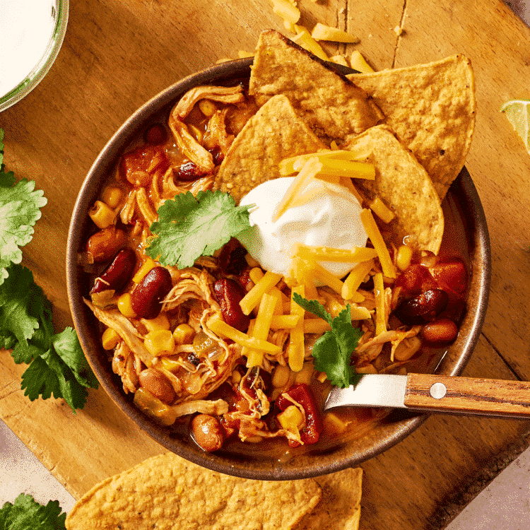 Featured image of chicken taco soup served in a bowl with toppings.