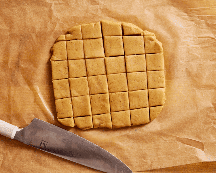 Cutting cookie dough into squares with a sharp knife.