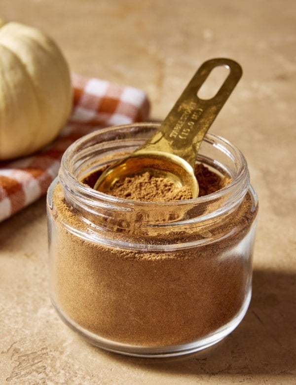 Homemade pumpkin spice in a jar with a measuring spoon.