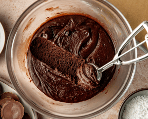Cookie scoop scooping out chilled dough out of clear mixing bowl.